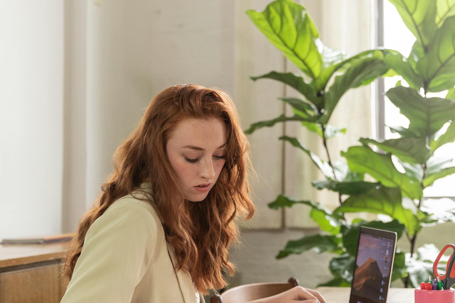 شخص يكتب ملخصاً مهنياً على حاسوبه المحمول مع مسودات مكتوبة في دفتر ملاحظات بجانبه